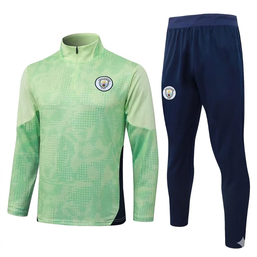 Unbranded (no Puma logo) Manchester City F.C. training kit including a 1/4 zip long-sleeved top (lime green with pixelated pattern) and matching pants (navy blue with pixelated pattern). The detailed Manchester City crest with three stars is prominent on the left chest and right thigh. The clean image is ready for a wholesale product page.